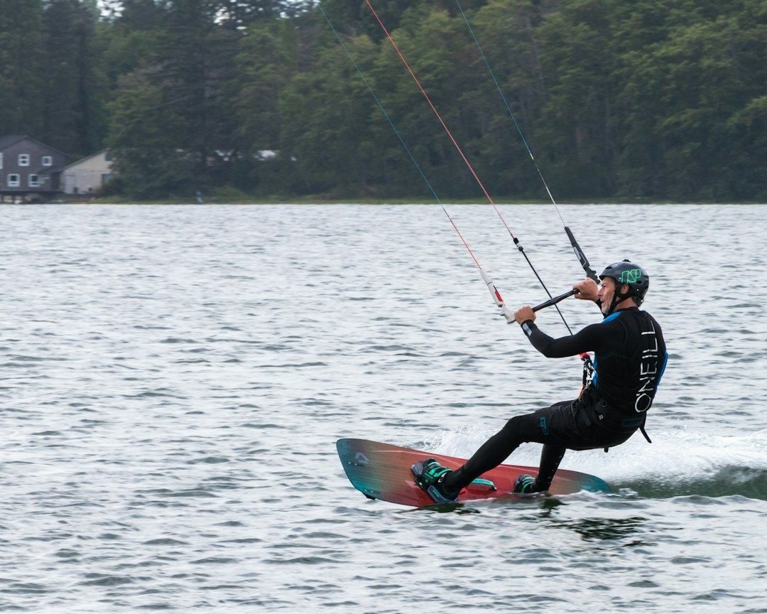 Kitesurfeur en combinaison noire, genoux fléchis sur une planche